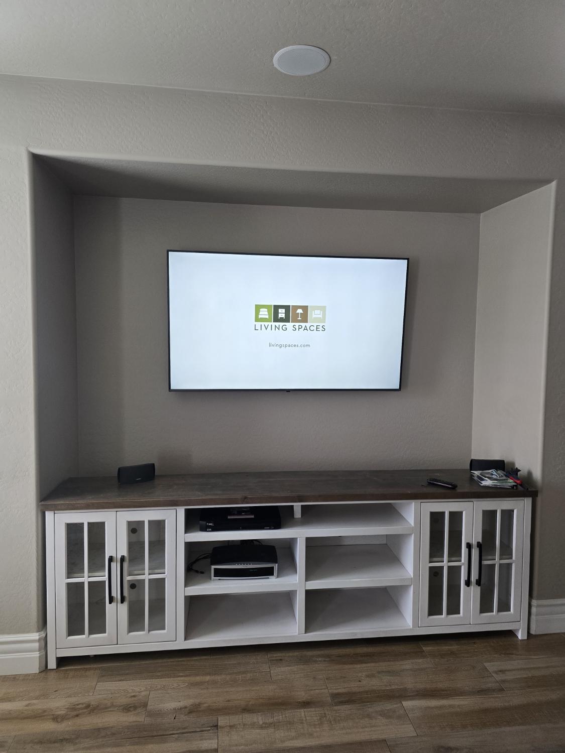 A television mounted level on the wall above a white console