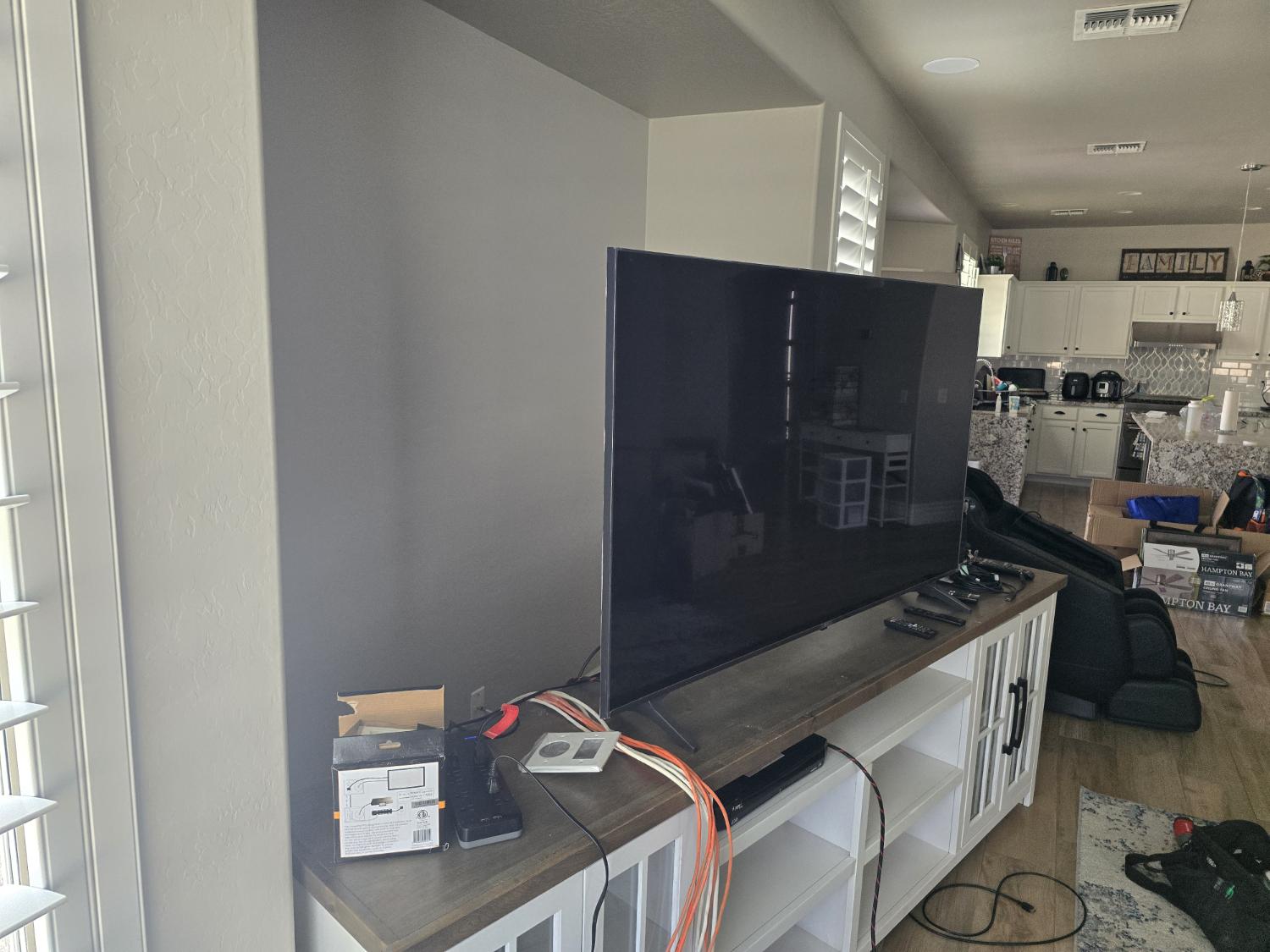 A television sitting on a console with loose cables before it was mounted