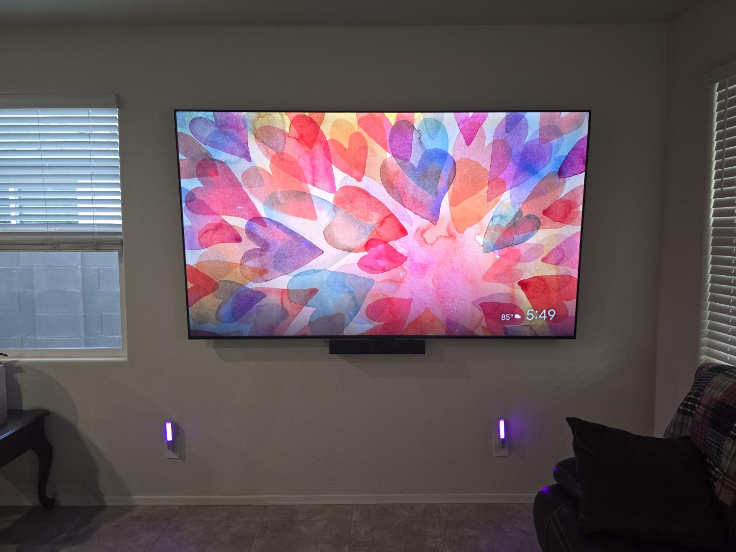 A television mounted on a living room wall with a soundbar underneath